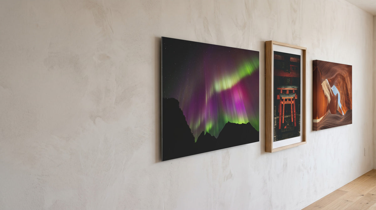 Trois tirages Benevolence accrochés sur un mur en plâtre : Aurore boréale sur les Lofoten sur alu Dibond, Torii vermillon en cadre bois, Antelope Canyon sur toile. Simulation.